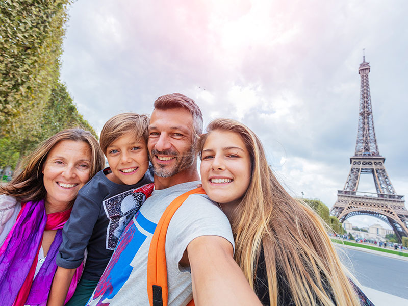 Family smiling taking selfie in front of Eiffel Tower